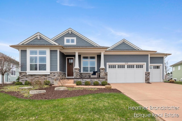craftsman house featuring concrete driveway, stone siding, a front yard, an attached garage, and a porch