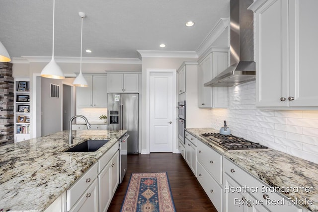 kitchen with appliances with stainless steel finishes, wall chimney range hood, a sink, visible vents, and crown molding