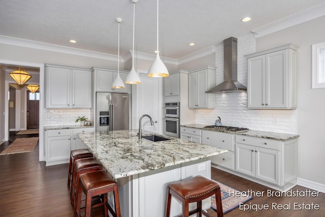 kitchen featuring appliances with stainless steel finishes, wall chimney range hood, dark wood-style flooring, a kitchen bar, and a sink