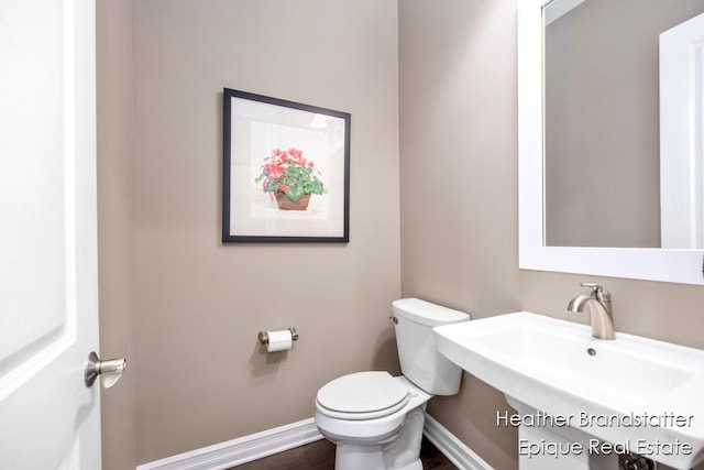 bathroom with toilet, a sink, wood finished floors, and baseboards