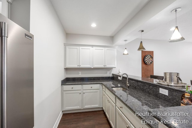 kitchen with dark stone counters, white cabinets, a sink, freestanding refrigerator, and dark wood finished floors