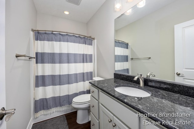 bathroom with toilet, vanity, curtained shower, and wood finished floors