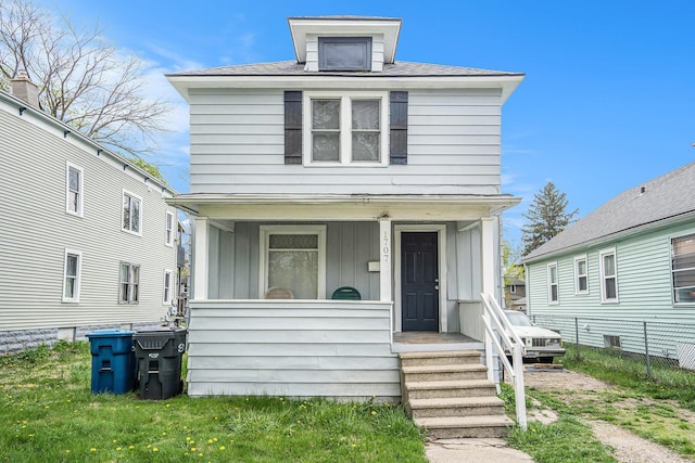 american foursquare style home featuring a porch, board and batten siding, and fence
