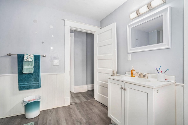 bathroom featuring wood finished floors, vanity, and a wainscoted wall