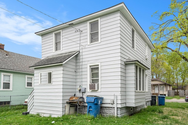 rear view of house with fence, a shingled roof, and a yard