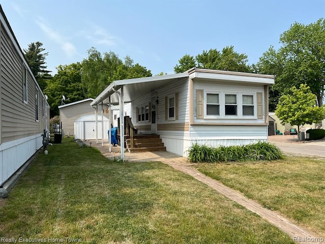 manufactured / mobile home featuring an outdoor structure, a front lawn, and a shed