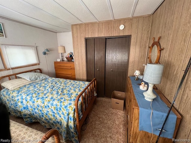 bedroom featuring wooden walls, carpet, and a closet