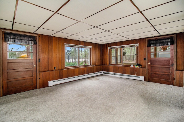 carpeted foyer entrance with a baseboard heating unit, a paneled ceiling, and wood walls