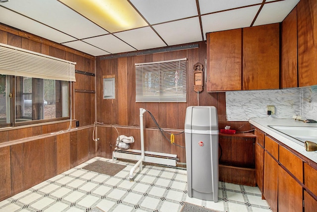 interior space with light floors, wooden walls, a baseboard heating unit, and a sink