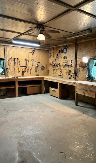 10773 Hamilton Rd, Irons, MI 49644 - misc room featuring a workshop area, unfinished concrete floors, wood walls, and ceiling fan