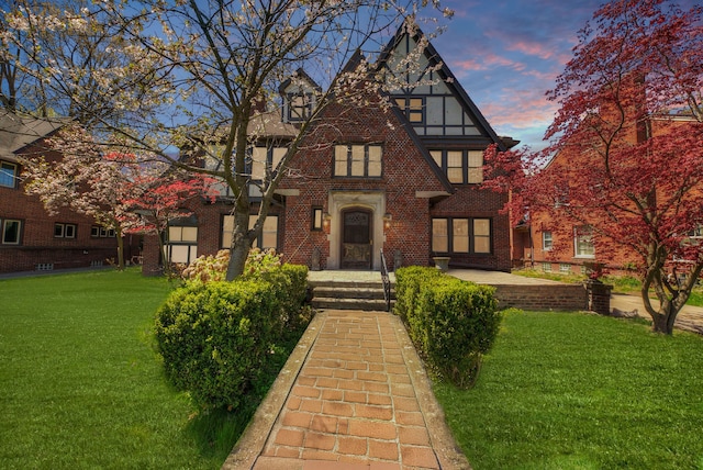 tudor house featuring brick siding and a front yard