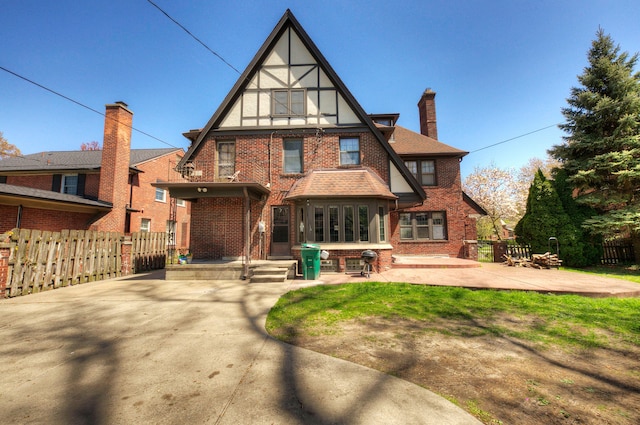back of property featuring brick siding, fence, a chimney, and a patio