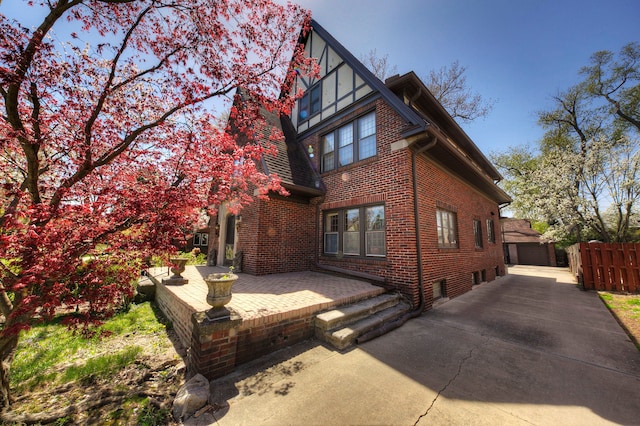 rear view of house featuring brick siding, a garage, and fence