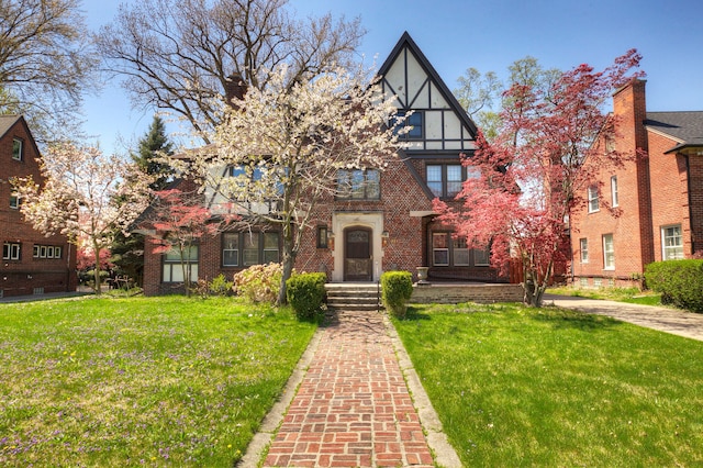 tudor home with brick siding and a front yard
