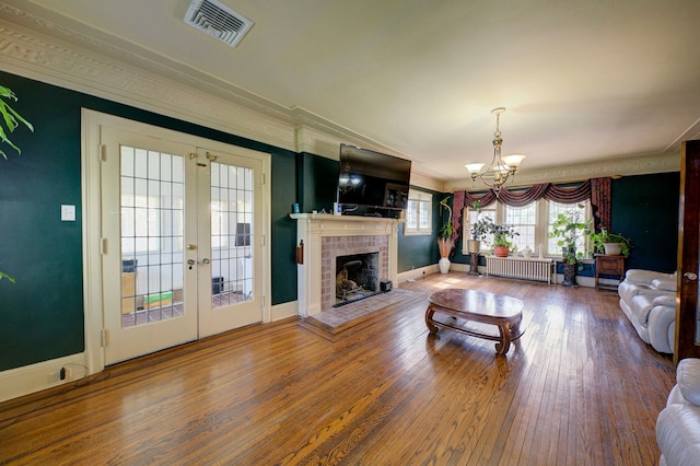 living area with an inviting chandelier, french doors, radiator heating unit, baseboards, and visible vents