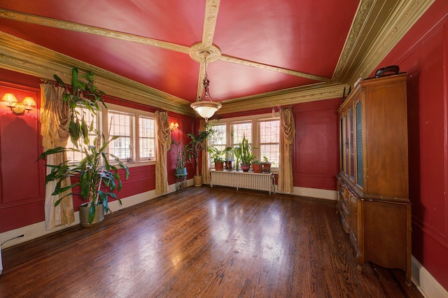 spare room featuring crown molding, baseboards, radiator, and wood finished floors
