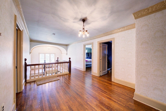 unfurnished room featuring baseboards, crown molding, wood finished floors, and a chandelier