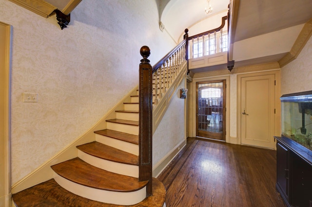 staircase with baseboards, wood finished floors, and a towering ceiling