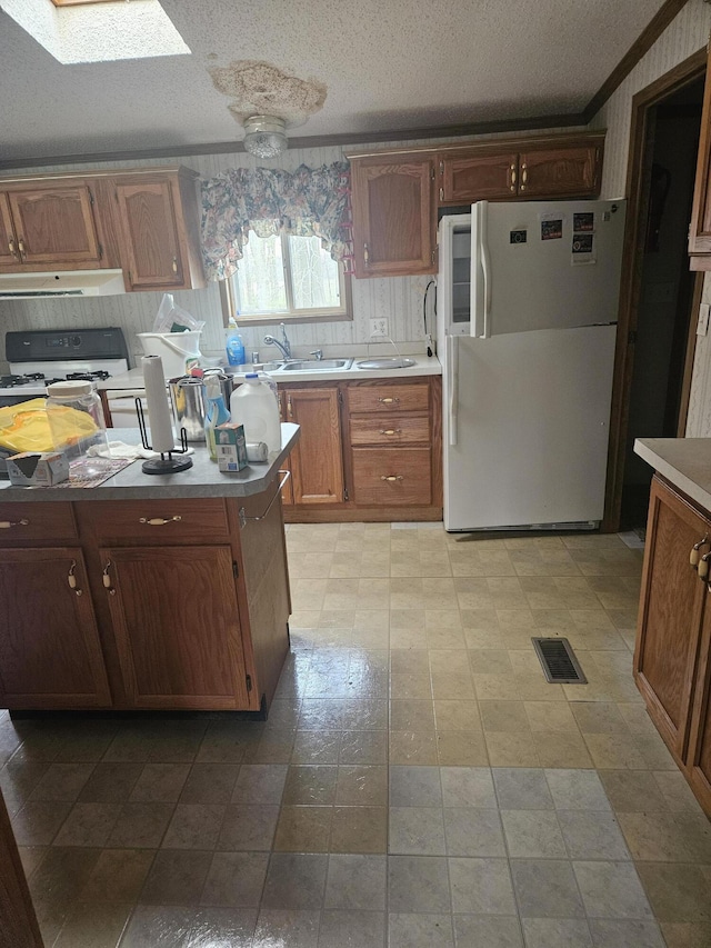 kitchen with visible vents, exhaust hood, light countertops, and freestanding refrigerator