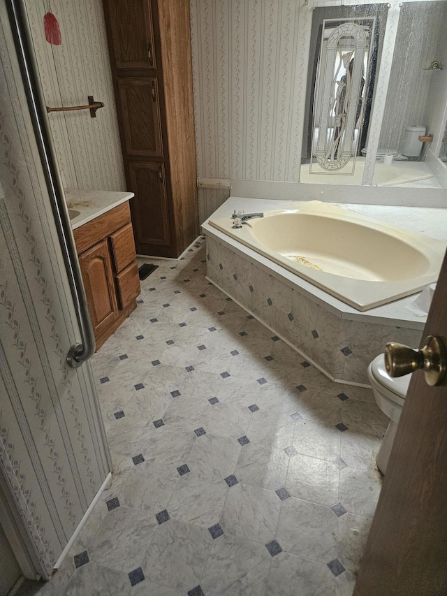 bathroom featuring vanity, a garden tub, toilet, and wallpapered walls