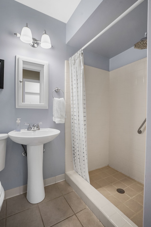 full bathroom with baseboards, a stall shower, toilet, and tile patterned flooring