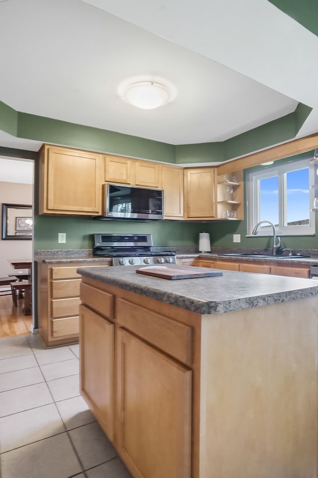 kitchen featuring light tile patterned floors, open shelves, a sink, stainless steel appliances, and a center island