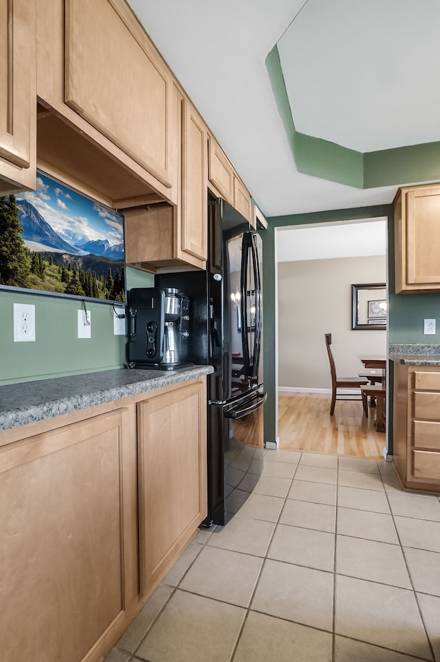 kitchen featuring baseboards, light tile patterned flooring, light brown cabinets, and freestanding refrigerator