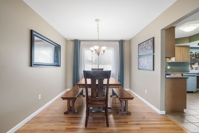 dining space with a notable chandelier, light wood-style flooring, and baseboards