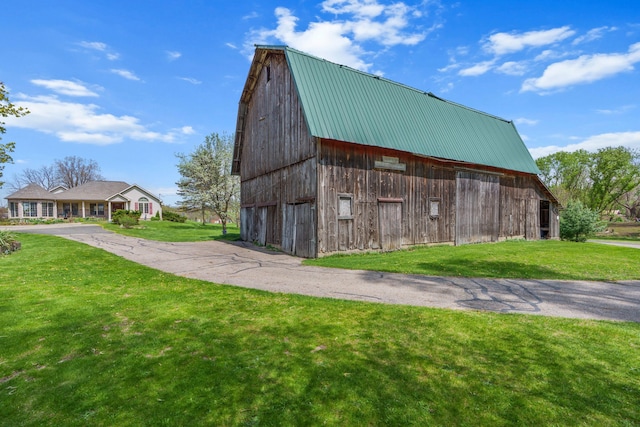 view of barn with a yard and driveway
