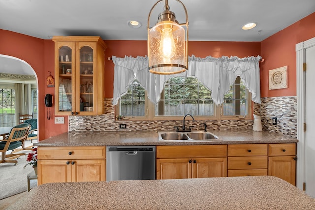 kitchen with a sink, glass insert cabinets, decorative backsplash, and stainless steel dishwasher