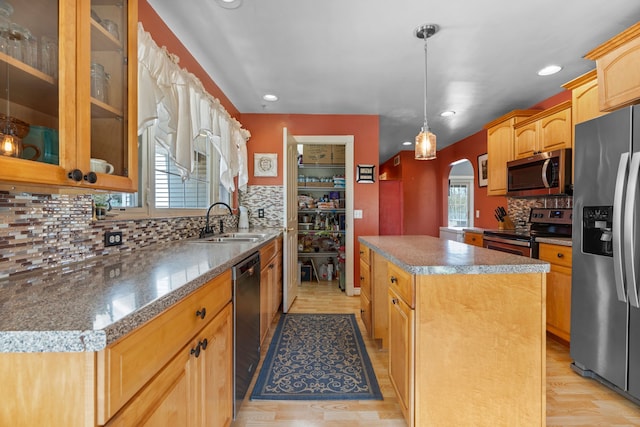 kitchen featuring a sink, arched walkways, a center island, stainless steel appliances, and tasteful backsplash