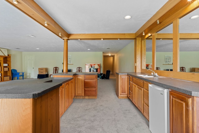 kitchen with a peninsula, light carpet, fridge, open floor plan, and a sink
