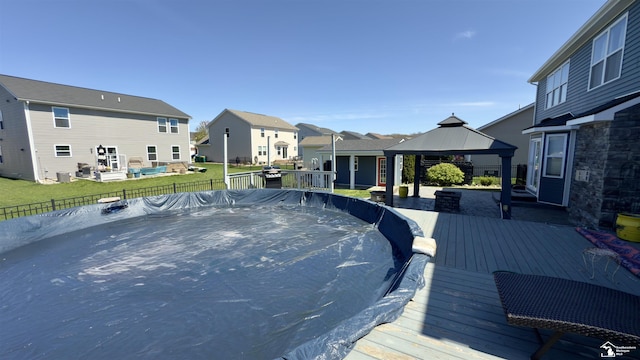 view of pool with a residential view, a wooden deck, a gazebo, and a yard
