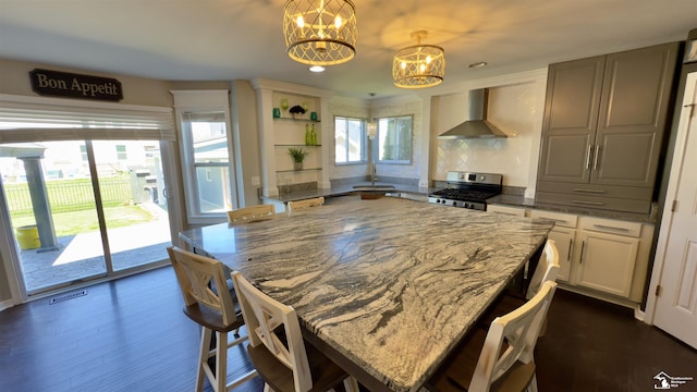 kitchen featuring an inviting chandelier, stainless steel range with gas cooktop, open shelves, a wealth of natural light, and wall chimney exhaust hood