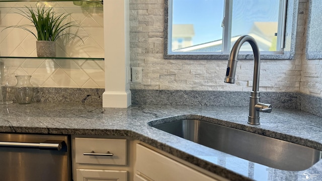 interior details with dark stone counters, dishwasher, a sink, and backsplash