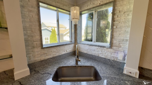 interior details with decorative light fixtures, stone counters, and a sink