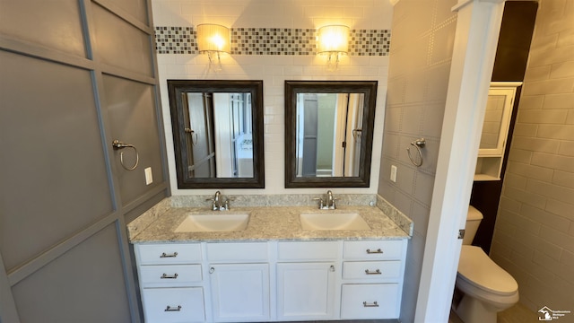 full bath with double vanity, toilet, and a sink