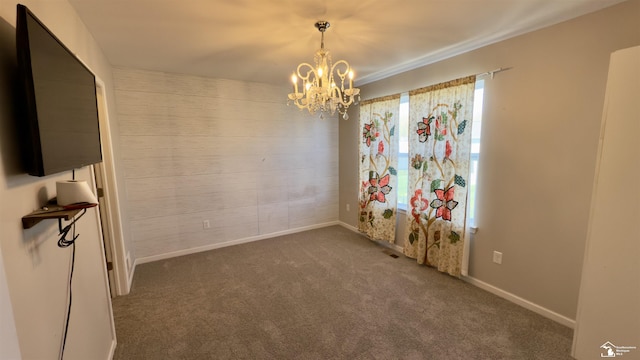 empty room featuring a notable chandelier, carpet floors, and baseboards