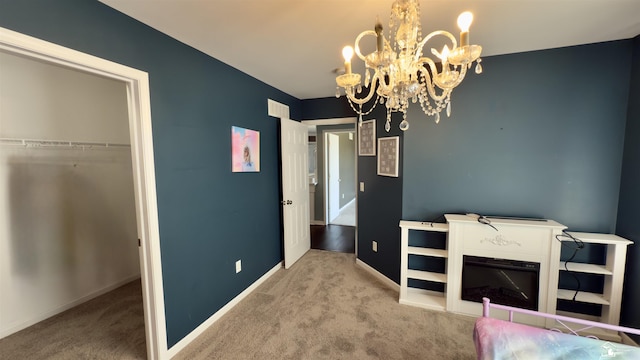 unfurnished bedroom featuring a closet, a chandelier, carpet floors, and baseboards
