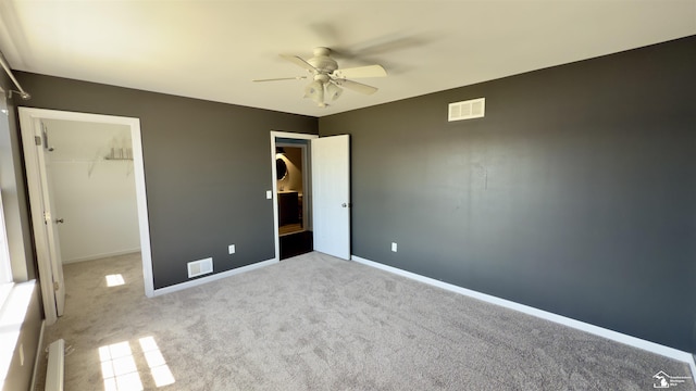 unfurnished bedroom with carpet flooring, a closet, visible vents, baseboards, and a spacious closet