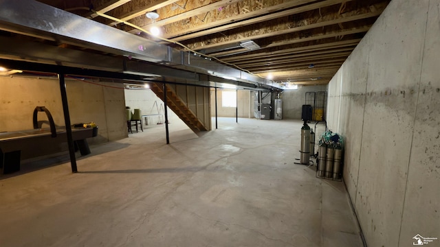 unfinished below grade area featuring water heater and stairway