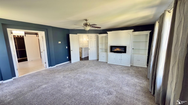 unfurnished bedroom featuring baseboards, ceiling fan, carpet flooring, and a glass covered fireplace