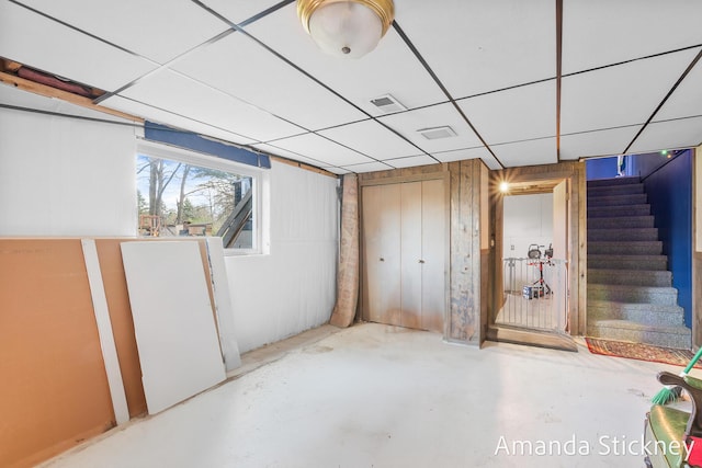 below grade area featuring visible vents, stairway, and a drop ceiling