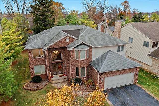 view of front facade with roof with shingles, brick siding, a garage, a chimney, and driveway