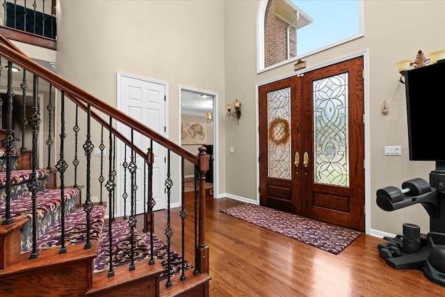 entryway with baseboards, a high ceiling, stairs, and wood finished floors
