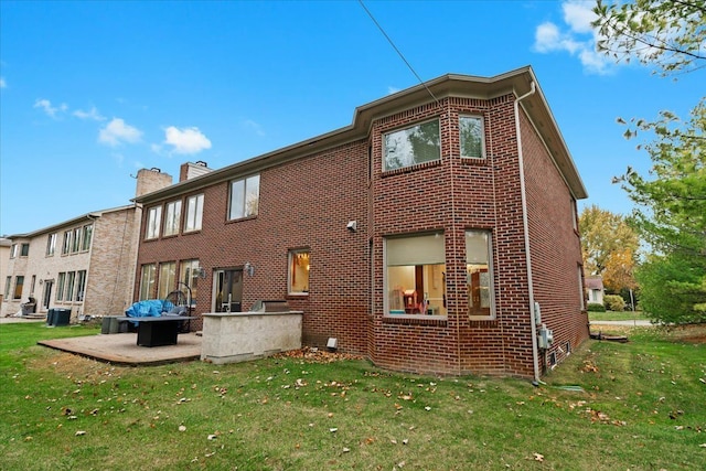 back of property with brick siding, central air condition unit, and a yard