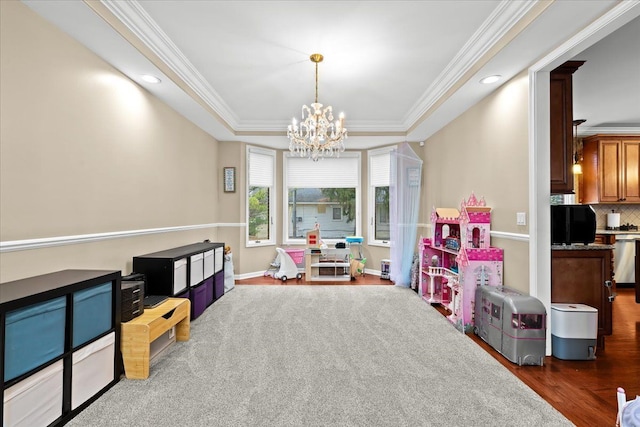 recreation room with crown molding, wood finished floors, recessed lighting, a tray ceiling, and a chandelier