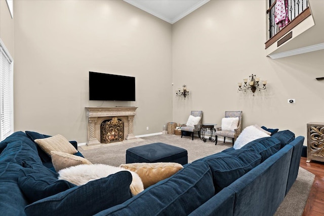 living area featuring a lit fireplace, a towering ceiling, crown molding, baseboards, and dark wood-type flooring