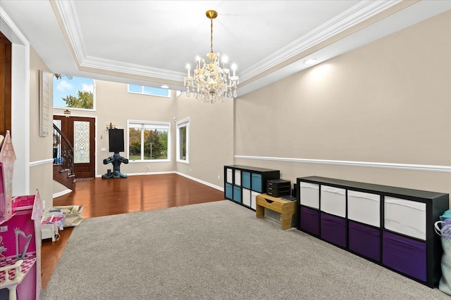 playroom with wood finished floors, a raised ceiling, baseboards, a notable chandelier, and ornamental molding