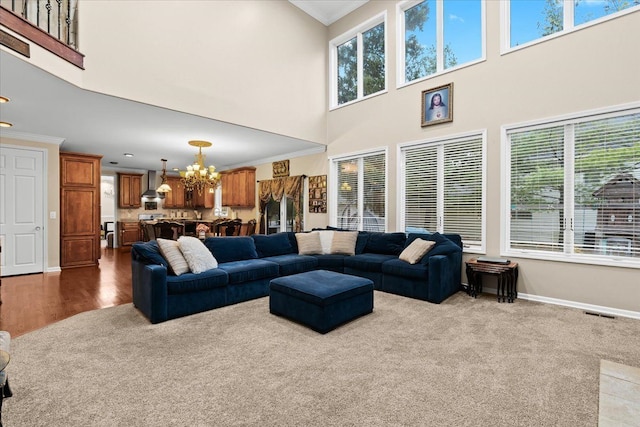 living room with crown molding, a high ceiling, a notable chandelier, and a wealth of natural light